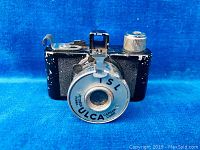 Front view of TSL ULCA subminiature spy camera showing lens markings and top shutter mechanism.