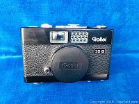 Front view of the camera showing lens cap, leather textured body, Rollei 35 B badge, and viewfinder elements.