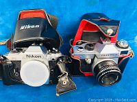 Two cameras side by side: Nikon FG with case and Praktica L8 with lens and case
