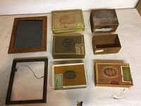 Top-down view of three wooden picture frames and five small wooden boxes with cigar branding and labels, arranged on a flat surface.