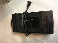 Black VHS tape rewinder with power cord coiled on top