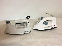 Two Proctor Silex irons shown side by side on a flat surface: a traditional steam iron and a simpler flat hand iron model 6200.