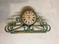 Battery operated round clock with Roman numerals on ornamental metal scroll stand