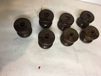 Seven vintage dark brown glass insulators arranged on a light surface.