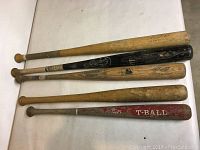 Image showing five wooden baseball bats, four Louisville Slugger branded and one T-Ball bat. They have signs of wear and use.