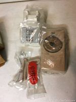 Old telephone push-button and rotary dial telephones, cords and parts in plastic wrapping on a flat surface