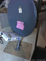 Full view of the gray satellite dish mounted on a bracket with labels attached.