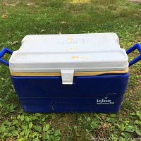Photo of large blue and white Igloo 54 qt cooler sitting on grass showing lid and body
