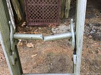 Close-up photo showing a mid-section rung of the aluminum ladder broken in half, and the ladder rails around it.