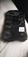 Front view of the large black overnight bag showing exterior pockets and handles.