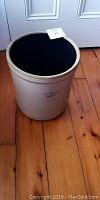 Photo of large off-white ceramic crock, shows cylindrical shape and worn rim.