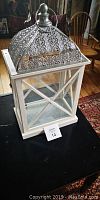 Full view of the wedding card holder showing the white wooden base with glass sides and silver filigree roof on top.
