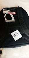 Back view of black Air Canada executive backpack showing padded straps, mesh back panel, and attached tags including Air Canada logo and lot number.