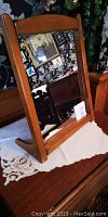 Mirror angled slightly to the left on a wooden table with floral wallpaper background.