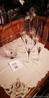 Wine decanter and 6 wine flutes on a table with a cream embroidered tablecloth