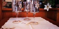 Set of 3 silvery decorative wine goblets shown standing on white tablecloth.