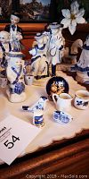 Photo showing various blue and white porcelain figurines including people in period clothing, two small pitchers, and bird figurines, arranged on a table.