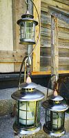 Front view of the metal candle holders showing the glass encased candle and copper-toned top on stands with curled feet.
