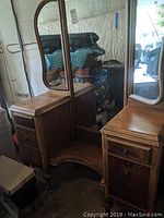 Overall front view of the vintage wooden vanity with three mirrors and drawer stacks on left and right sides, placed in a garage setting.