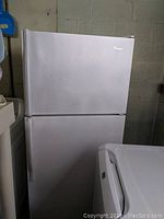 Front and side views of white Whirlpool refrigerator with top freezer.