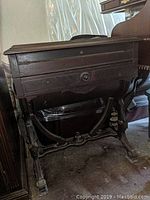 Front and side view of the antique compact desk showing carved wooden legs, decorative supports, drawer with knob and keyhole.