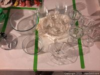 Full view of clear glass bowls, sauce bowls, decanter, gravy boat, and sandwich/dessert plates with cups on table.