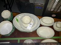 Overhead view of stacked plates, bowls, cups and saucers with platters to right