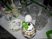 Overview photo of cut glass decanter, three cut glass canisters, and various trinket boxes including oval and heart-shaped floral designs.