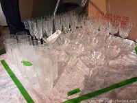 Photo showing the full spread of Lenox crystal glassware on a white cloth, including tall glasses and martini glasses arranged in rows.