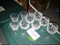 Ten Waterford stemware glasses arranged on a green plastic container lid, showing overall lot quantity and crystal cut pattern.