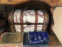 Photo showing vintage books and decorative storage trunk with map print.