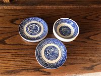 Several blue and white china plates stacked showing detailed Asian-inspired patterns including birds and geometric motifs.