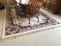 Large floral area rug under dining table showing whole rug and fringe edges