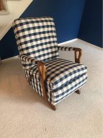 Side angle view of rocking chair showing wooden armrest and plaid fabric upholstery