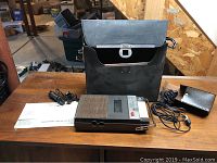 Photo showing Sears cassette recorder, carrying case, power cord, external microphone or earpiece, and instruction manual on wood table.