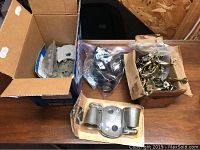 Four boxes containing various pieces of new Schlage door hardware including mounting plates and door levers