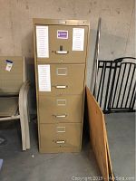 Front view of beige metal 4 drawer file cabinet with label holders and handles on drawers.