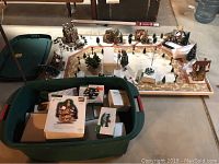 Wide angle of entire display platform with glued houses, trees, and sidewalk. Green storage bin containing original boxes and more collectibles in foreground.