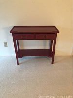 Front view of red painted side table with two drawers and lower shelf