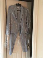 Full view of the navy and white checkered Calvin Klein suit hanging on door covered in plastic, showing blazer and matching pants.