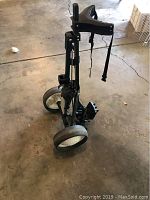 Full view of folded Spaulding golf push cart showing frame, handle, and wheels.