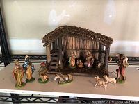 Full view of the nativity set showing stable, figurines spread around including the missing ear on donkey