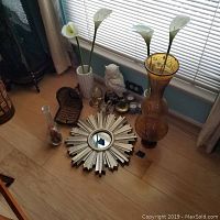 Image showing starburst mirror, amber glass vase, white textured vase with faux flowers, glass swans, owl figurine, candles, and unicorn canister arranged on floor