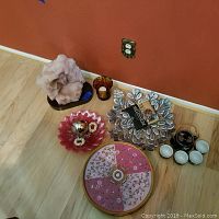 Six items including figurine, candle vase, glass bowl, tea set, foot stool and metal leaf wall art shown on wooden floor against red wall