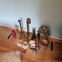 Overall view of assortment containing brass and ceramic candle holders, coasters, utensil holder, salt and pepper shakers, ash trays, and decorative items.