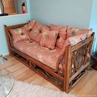 Front side of the bamboo framed couch with floral striped cushions and pillows arranged on it