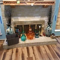 Set of 6 glass vases on a hearth in front of fireplace, showing size, shape, and color variety.