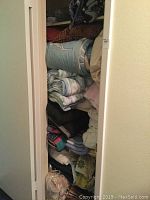Closet filled with stacked folded comforters, bed linens, blankets, and towels.