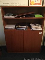 Front view of the brown wood cabinet with bookcase top, adjustable shelves, and lower cabinet doors. Various papers on shelves (not included).