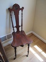 Full view of antique wooden chair showing rail back with circular carved motif, shaped seat, and claw feet legs.